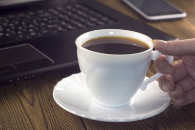 Ahşap arka plan üzerinde beyaz kahve Kupası laptop telefon el