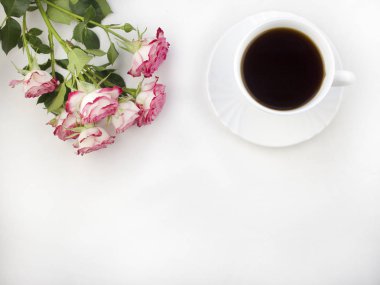Bir fincan kahve beyaz bir arka plan ve güller