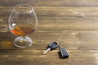 Arabanın anahtarlarını ve ahşap arka plan üzerinde alkol ile bir bardak