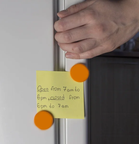 Hand opening refrigerator door and yellow sticker