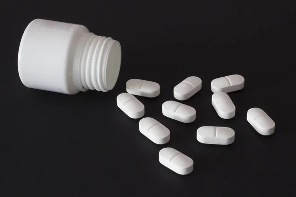 Tabletki na czarnym tle z słoik — Zdjęcie stockowe
