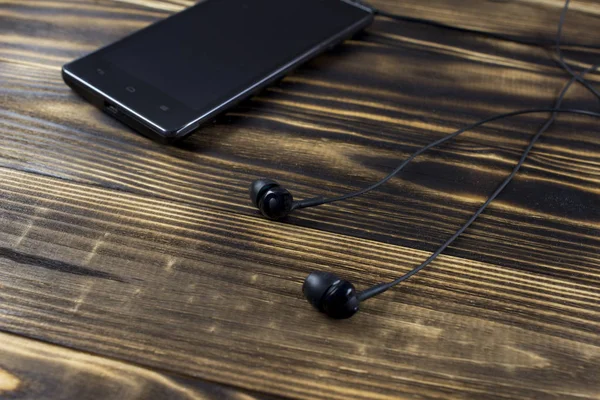 Teléfono negro con auriculares negros sobre fondo de madera —  Fotos de Stock