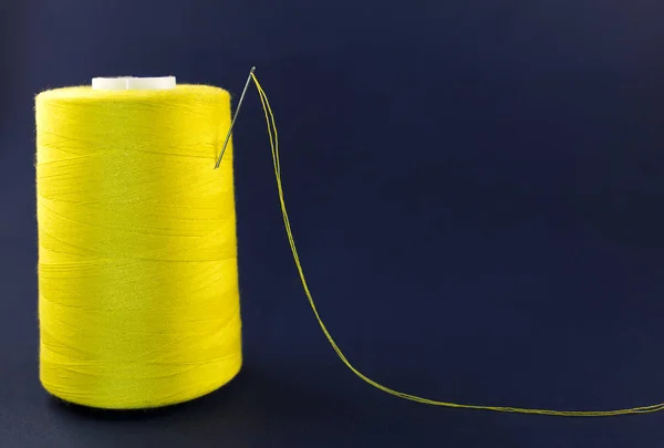 Esquisse jaune de fil avec une aiguille sur un fond bleu — Photo