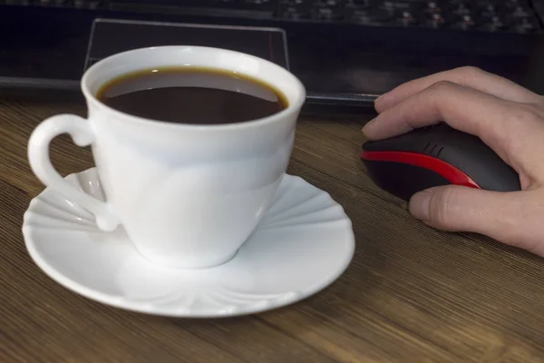 Uma xícara de café computador, mouse, mão, fundo de madeira — Fotografia de Stock