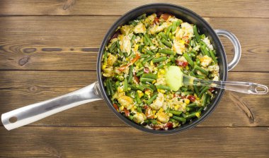 Bir tavada bir ahşap zemin üzerine haşlanmış sebze