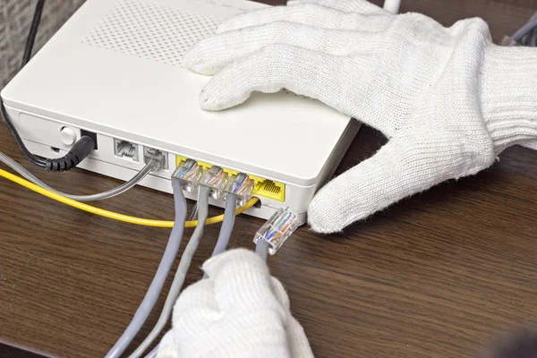 Um homem conecta um cabo de rede ao modem, um close-up — Fotografia de Stock