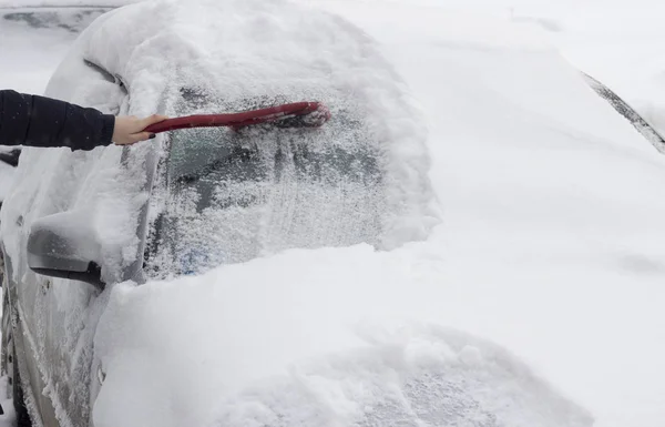La chica cepilla el coche de la nieve con un cepillo — Foto de Stock