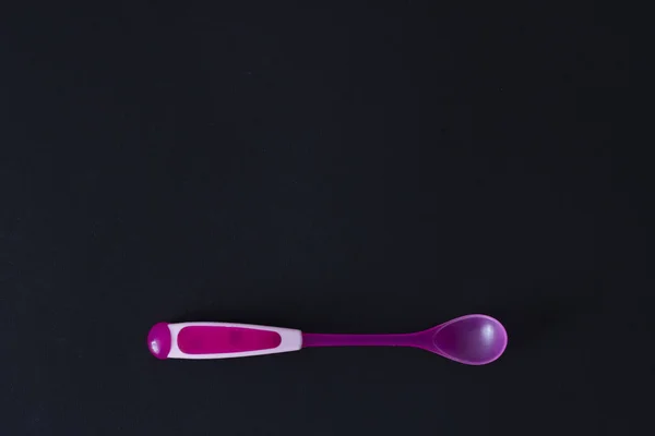 Cucchiaio rosa bambino su uno sfondo nero — Foto Stock