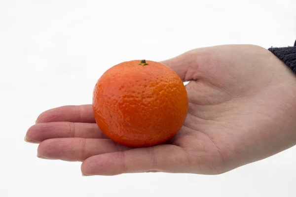 Mandarin in hand against the background of snow — Stock Photo, Image