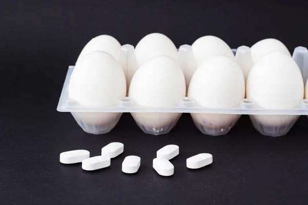 Tacy jaj kurzych, na czarnym tle i obok kłamstwo pill antybiotyków, zbliżenie — Zdjęcie stockowe