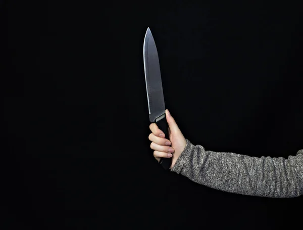 Hand of a girl with a knife on a black background, close-up, knife