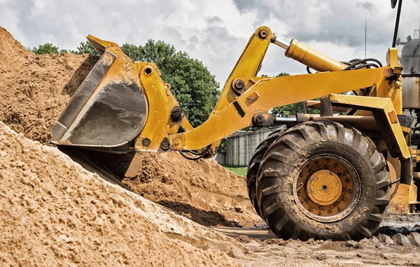 Yellow tractor loader is picking up a bucket of earth, mechanical, ladle with earth — Stock Photo, Image