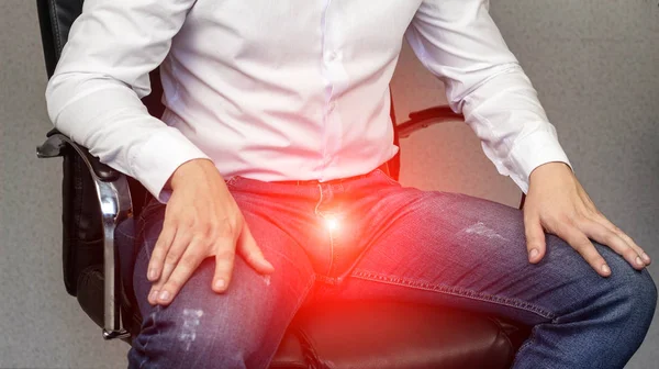 A man sits in an office chair, sore groin, crotch, prostatitis, close-up — Stock Image A man sits in an office chair, sore groin, crotch, prostatitis, close-up Royalty Free Stock Images