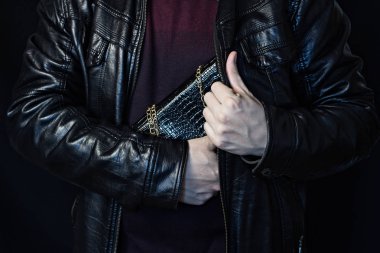 Bir adam bir kadının çantası onun koynunda bir çanta, siyah bir arka plan, çanta hırsızlığı hırsızlık gizler.
