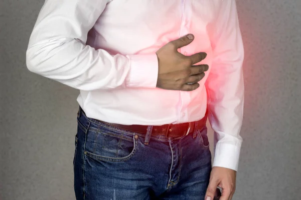 Un hombre con camisa blanca se aferra al abdomen, dolor abdominal, acidez estomacal, primer plano —  Fotos de Stock