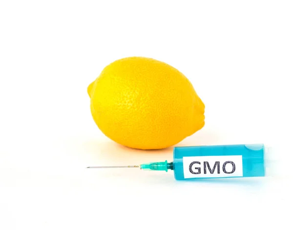 Limón sobre fondo blanco junto al cual hay una jeringa con gmo y nitratos, primer plano, organismo modificado genéticamente —  Fotos de Stock