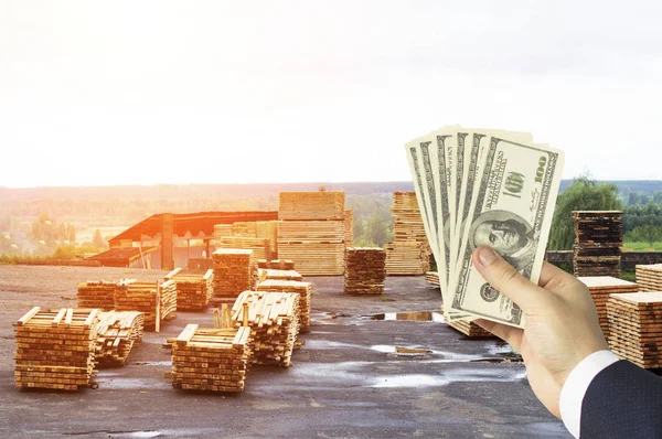 Ręka z pieniędzy dolarów na tle składu z gotowych płyt, drewna, Szalunki, dolarów — Zdjęcie stockowe