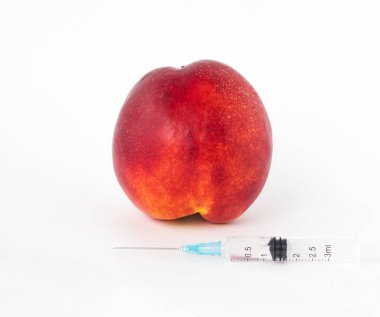 Nektarin beyaz bir arka plan üzerinde sonraki bir şırınga GDO ve nitrat, yakın çekim, genetiği değiştirilmiş organizma olduğunu