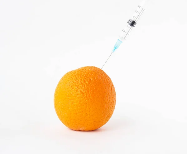 Naranja sobre un fondo blanco en el que entran gmo y nitratos, primer plano, organismo modificado genéticamente, naranja —  Fotos de Stock