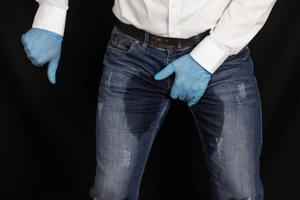 Un hombre con guantes médicos y pantalones mojados muestra un gesto de vergüenza, prostatitis, incontinencia — Foto de Stock