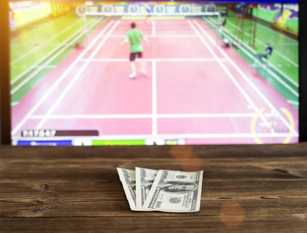 Pieniądze dolarów na tle telewizor na którym idzie badmintona, bukmacherski, zakłady bukmacherskie — Zdjęcie stockowe