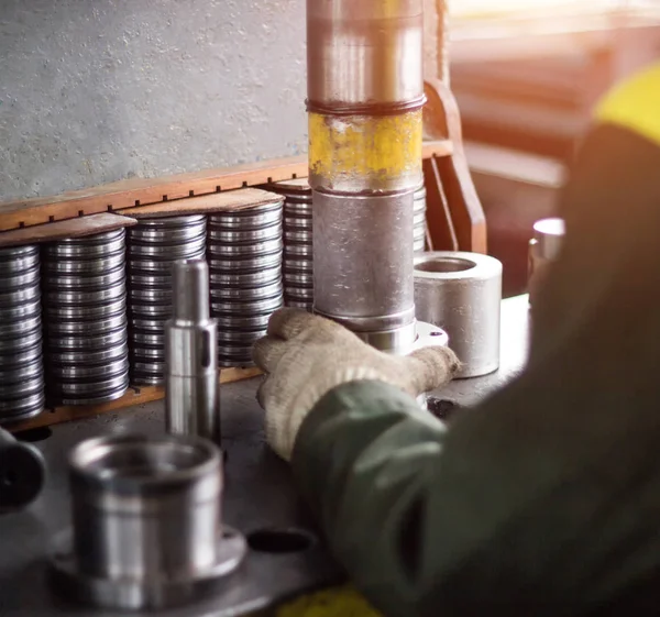 The worker assembles the pressing of the bearing into a metal clip on the machine, assembles the finished unit, close-up, factory — Stock Photo, Image