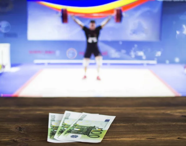 Euro money on the background of TV on which show weightlifting, sports betting, bookmaker