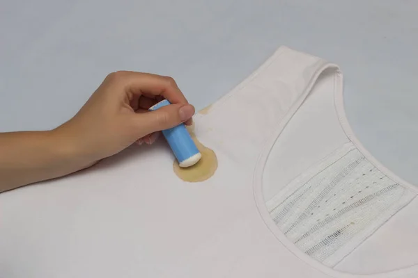 Fille enlève la tache nettoie avec un crayon détachant, gros plan, main, crayon détachant, T-shirt blanc — Photo
