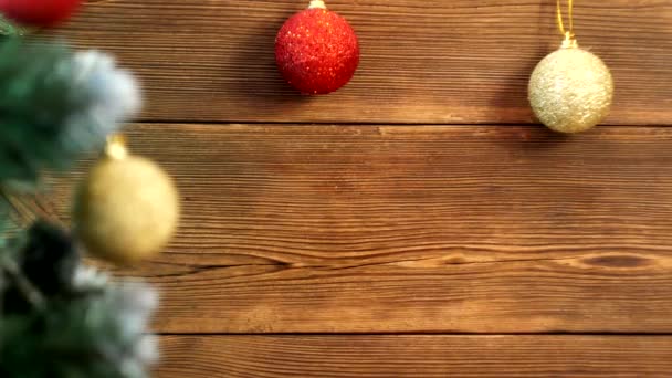 Fondo de Navidad de madera con bolas de Navidad de diferentes colores y un árbol de Navidad en el que se queman las luces de Navidad, lugar para el texto, decoración — Vídeo de stock