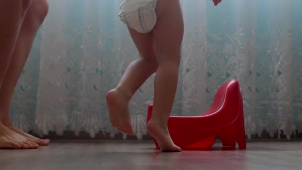 Mother teaches little baby to walk on the pot, schooling a child to the pot, childrens potty — Stock Video