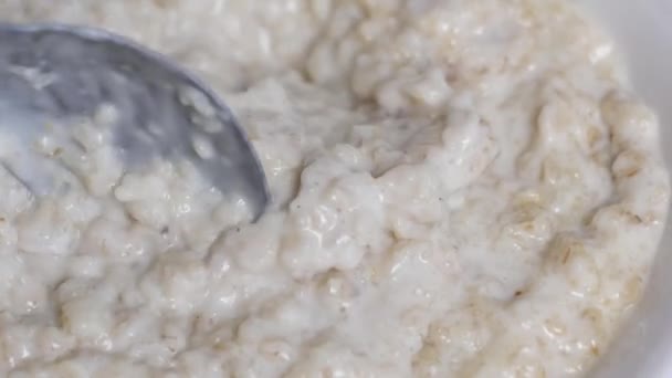 Cocina de avena, revolviendo la avena con una cuchara, primer plano, desayuno — Vídeos de Stock