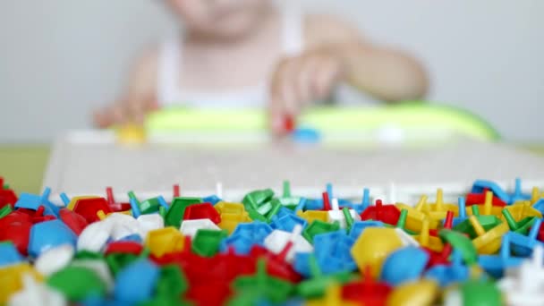 Kind spielt ein Spiel zur Entwicklung motorischer Fähigkeiten, sammelt ein buntes Designer-Mosaik für Kinder, Entwicklung des Denkens, lernt Farben — Stockvideo