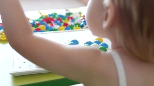 Küçük bir kız bir oyun oynar, motor becerileri geliştirme ve düşünme çocuklar, yakın çekim, eğitim, Kafkas geliştirir, çok renkli bir mozaik çalışır — Stok video