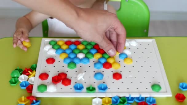 Una bambina gioca un gioco, elabora un mosaico multicolore che si sviluppa, sviluppando abilità motorie e pensando nei bambini, primo piano, istruzione, caucasico — Video Stock