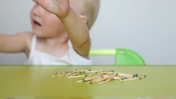 Un niño pequeño juega con cerillas en la mesa, fondo blanco, caucásico, peligro — Vídeos de Stock