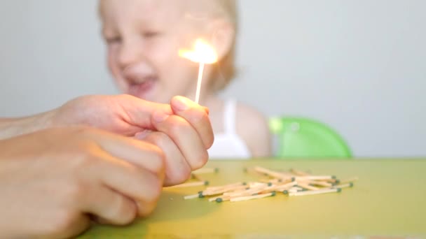 Die Mutter zündet die Streichhölzer an und lehrt das kleine Kind, dass die Kinder keine Streichhölzer nehmen können, die Folgen des Feuers, das Kind bläst auf das Streichhölzchen — Stockvideo