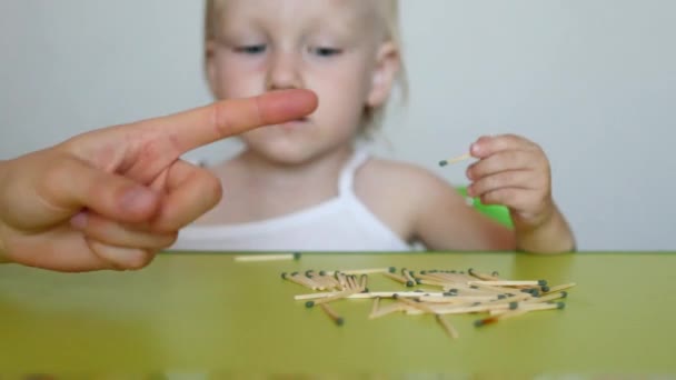 Die Mutter zündet die Streichhölzer an und lehrt das kleine Kind, dass die Kinder keine Streichhölzer nehmen können, die Folgen des Feuers, das Kind bläst auf das Streichhölzchen — Stockvideo