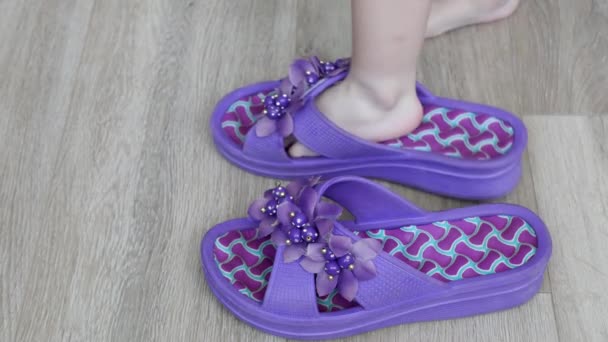 Un niño pequeño camina en zapatillas grandes para adultos alrededor de la casa, zapatillas para adultos con pies de niño, hogar — Vídeo de stock