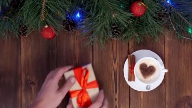 Mens eller bir hediye ve kahve masa, ahşap arka plan, yeni yıl, yeni yıl tatilleri, boşluk için bir hediye almak