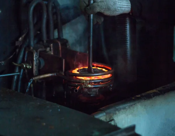 The worker makes hardening heat treatment of the metal gear on a special machine, close-up, hardening of metal, quenching