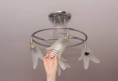 Enerji tasarrufu sağlayan modern spiral ampul asma tavan, enerji tasarrufu, el, yakın çekim, ekonomik bir avize yükleme
