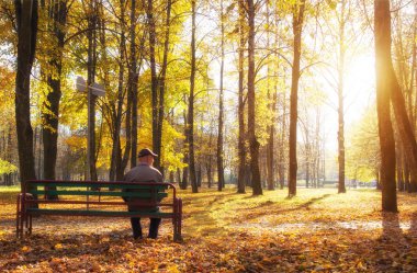 Yaşlı adam bir şehir parkı, emeklilik, sonbahar park ve güneş, emeklilik, vesayet bir bankta oturan emekli