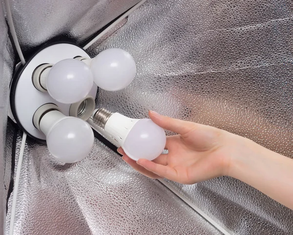 Installing a diode energy saving light bulb in a soft box for lighting, hand, close-up, home, arm — Stock Photo, Image