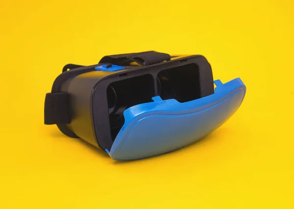 Modernas gafas azules de realidad virtual para smartphone y teléfono sobre fondo amarillo, primer plano, multimedia, simuladas por ordenador, videojuegos —  Fotos de Stock