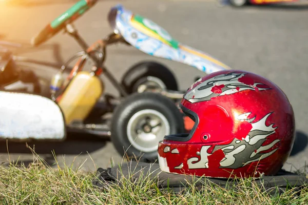 Competiciones de karting, un casco protector rojo se encuentra en el fondo de la carrera de carros, primer plano —  Fotos de Stock