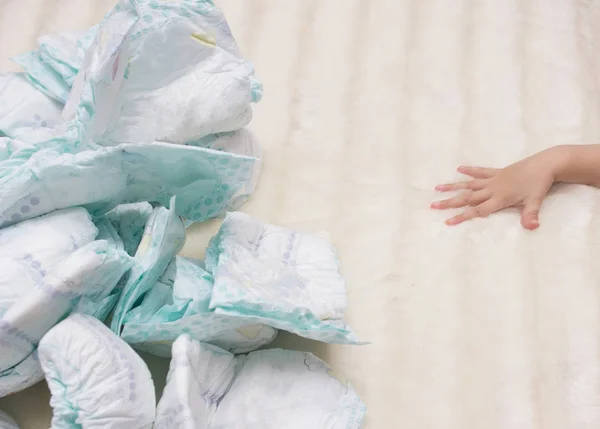 Stack of baby diapers on a white background and a baby hand, nappy — Stock Photo, Image