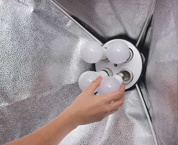 Installing a diode energy saving light bulb in a soft box for lighting, hand, close-up, industry, electrician, electricity — Stock Photo, Image