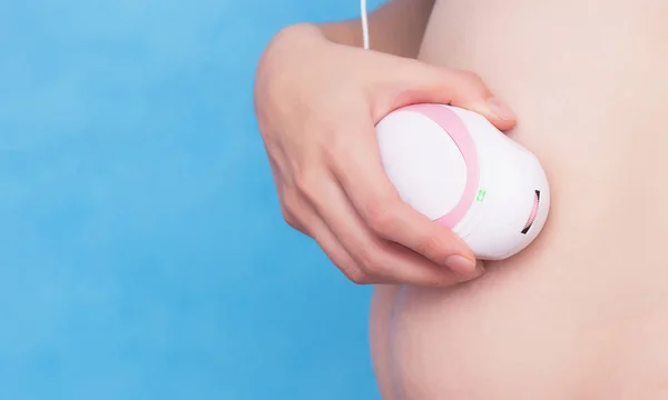 Chica embarazada sostiene en su mano un doppler fetal cerca del abdomen y escucha los latidos del corazón del niño, primer plano, estómago — Foto de Stock