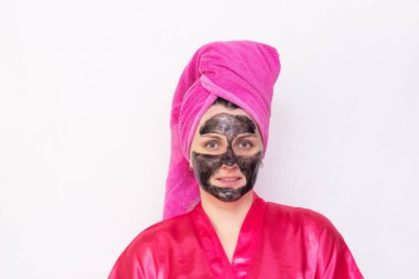 Bir kız beyaz bir arka plan üzerinde siyah nokta ve pembe bir elbise içinde siyah noktalara karşı yüzünde siyah bir maske ve bir havlu başında, kopyalama alanı