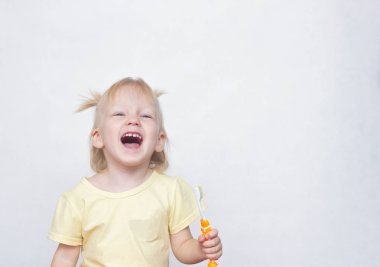 Bir diş fırçası onun elinde tutan ve beyaz bir arka planda kopya alanı, açık ağzı ile gülüyor küçük mavi gözlü sarışın kız beyaz